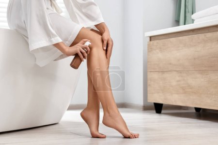 Foto de Mujer aplicando producto auto-bronceado en su pierna en la bañera en el baño, primer plano. Espacio para texto - Imagen libre de derechos