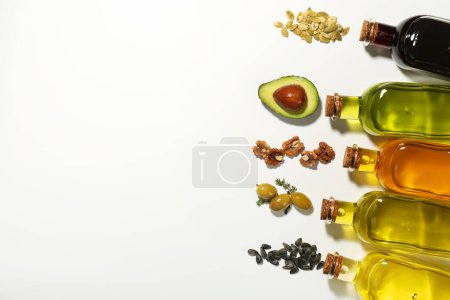 Photo for Vegetable fats. Different cooking oils in glass bottles and ingredients on white background, flat lay. Space for text - Royalty Free Image
