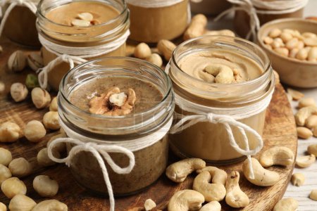 Photo for Tasty nut butters in jars and raw nuts on table, closeup - Royalty Free Image