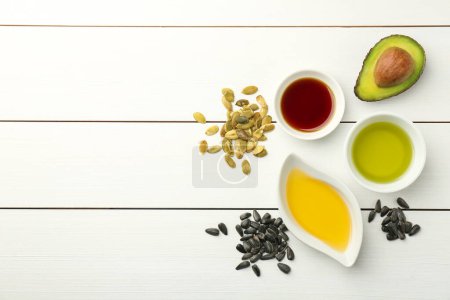 Photo for Vegetable fats. Different cooking oils in bowls and ingredients on white wooden table, flat lay. Space for text - Royalty Free Image