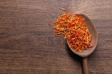 Aromatic saffron and spoon on wooden table, top view. Space for text