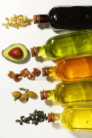 Photo for Vegetable fats. Different cooking oils in glass bottles and ingredients on white background, flat lay - Royalty Free Image