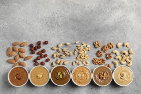 Photo for Tasty nut butters in bowls and raw nuts on light grey background, flat lay - Royalty Free Image