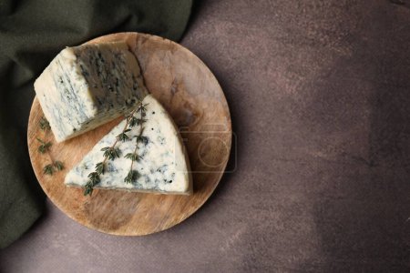 Tasty blue cheese with thyme on brown table, top view. Space for text
