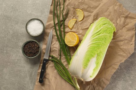 Fresh Chinese cabbage, lemon, green onion and spices on light grey table, flat lay