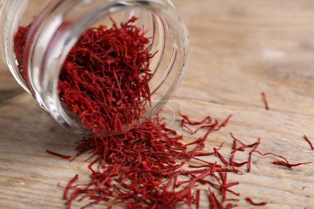 Aromatic saffron in glass jar on wooden table, closeup