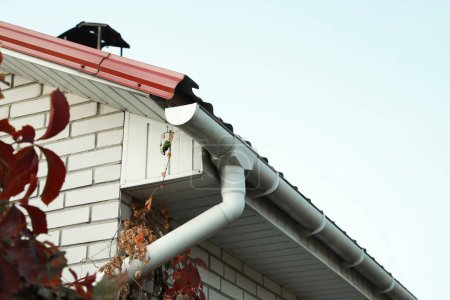 Rain gutter system with drainpipe on house outdoors