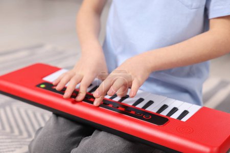Little boy playing toy piano at home, closeup