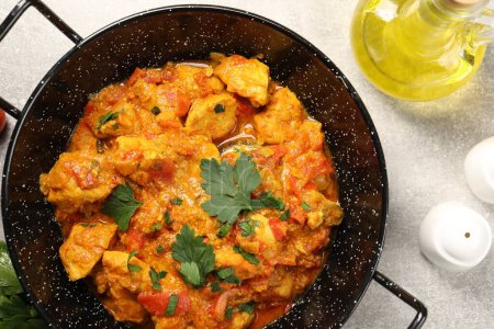 Delicioso curry de pollo en sartén y aceite sobre mesa gris claro, vista superior
