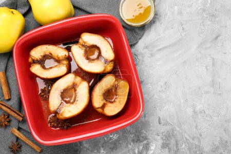 Tasty baked quinces with honey in dish on grey textured table, flat lay. Space for text