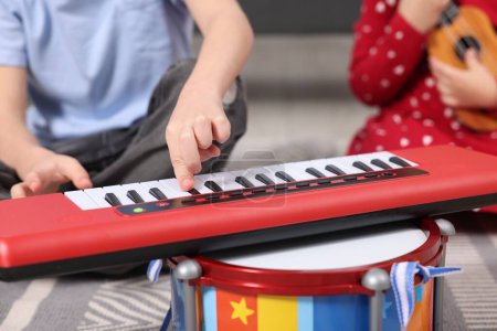 Little children playing toy musical instruments at home, closeup