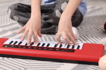 Little boy playing toy piano at home, closeup