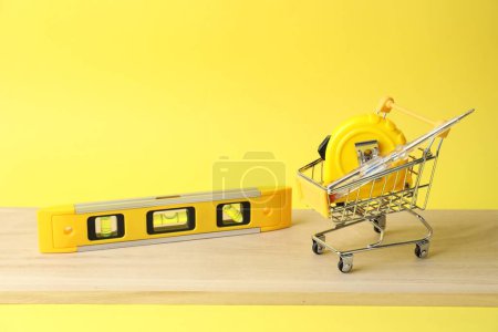 Téléchargez les photos : Petit panier et ensemble d'outils de construction sur fond jaune - en image libre de droit