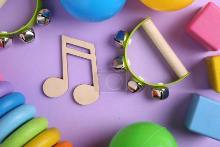 Herramientas para crear canciones para bebés. Composición plana con nota de madera y panderetas para niños sobre fondo violeta