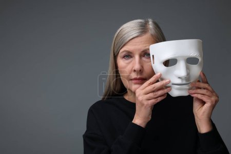 Concept de personnalité multiple. Femme avec masque sur fond gris, espace pour le texte