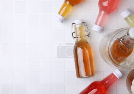 Leckere Kombucha in Glasflaschen auf weißem Kacheltisch, flach gelegt. Raum für Text