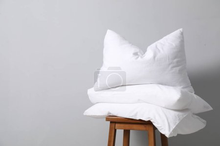 Soft pillows on chair neal light grey wall, space for text
