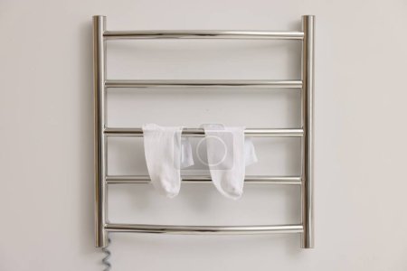 Beheizter Handtuchhalter mit Socken an weißer Wand
