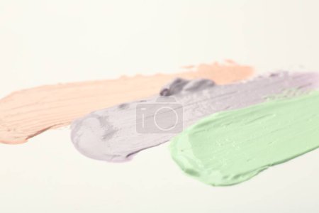 Photo for Strokes of pink, green and purple color correcting concealers on white background, closeup - Royalty Free Image