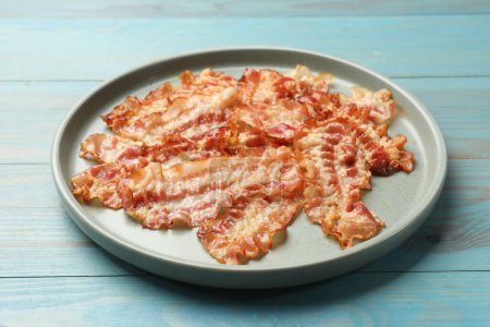 Photo for Delicious fried bacon slices on blue wooden table - Royalty Free Image