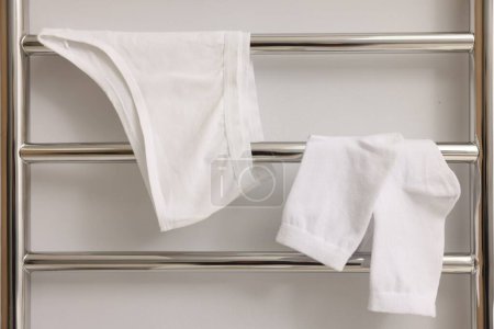 Beheizter Handtuchhalter mit Unterwäsche und Socken an weißer Wand, Nahaufnahme