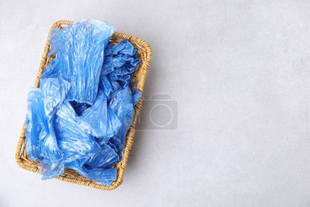 Photo for Blue medical shoe covers in wicker basket on light background, top view. Space for text - Royalty Free Image