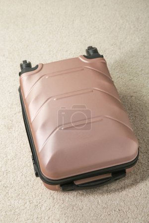 Stylish suitcase packed for travel on beige rug