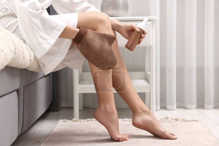 Foto de Auto-bronceado. Mujer que aplica el producto cosmético en la pierna con el guante de bronceado en la cama en casa, primer plano. Espacio para texto - Imagen libre de derechos