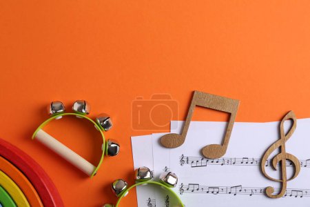 Tools for creating baby songs. Flat lay composition with tambourines for kids on orange background. Space for text