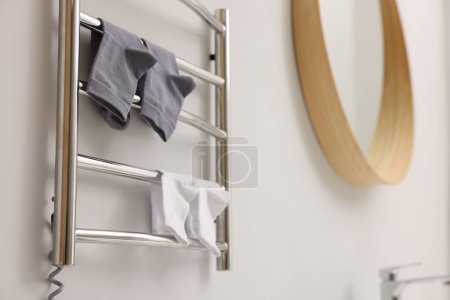 Photo for Heated towel rail with socks on white wall in bathroom - Royalty Free Image