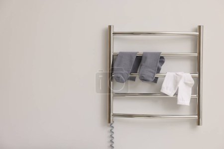 Photo for Heated towel rail with socks on white wall, space for text - Royalty Free Image