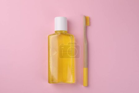 Foto de Enjuague bucal fresco en botella y cepillo de dientes sobre fondo rosa, vista superior - Imagen libre de derechos