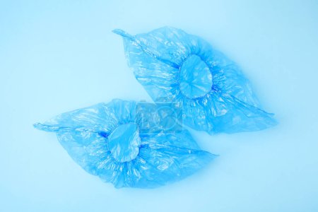 Pair of medical shoe covers on light blue background, top view