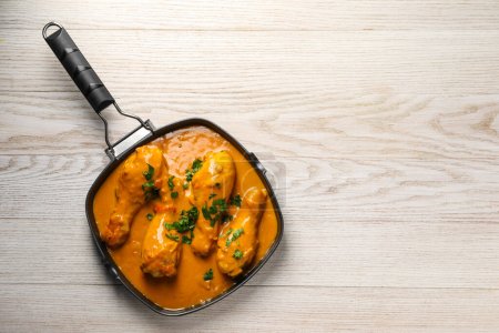 Sabroso pollo al curry con perejil en la mesa de madera, vista superior. Espacio para texto