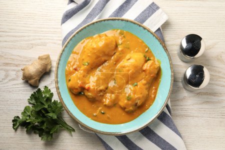 Curry de poulet savoureux, persil et gingembre sur table en bois, plat