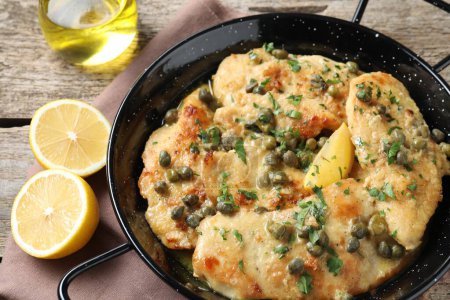 Delicious chicken piccata with herbs on wooden table