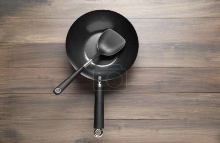 Photo for Black metal wok and spatula on wooden table, top view - Royalty Free Image