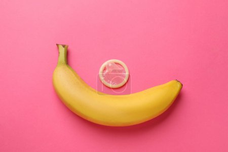 Téléchargez les photos : Banane et préservatif sur fond rose, plat. Concept de sexe sûr - en image libre de droit