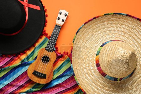 Téléchargez les photos : Chapeaux sombrero mexicains, guitare et poncho coloré sur fond orange, pose plate - en image libre de droit