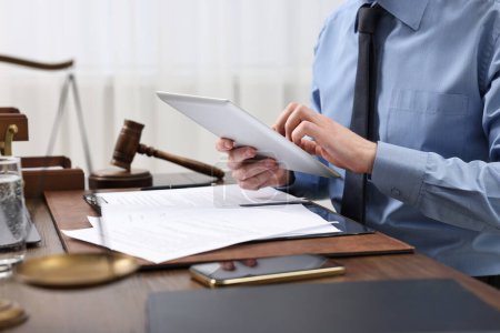 Photo for Lawyer using tablet at wooden table, closeup - Royalty Free Image