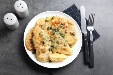 Delicious chicken piccata with herbs served on grey table, flat lay