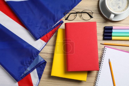 Fremdsprachen lernen. Verschiedene Bücher, Flagge des Vereinigten Königreichs, Schreibwaren und Gläser auf Holztisch, flach gelegt