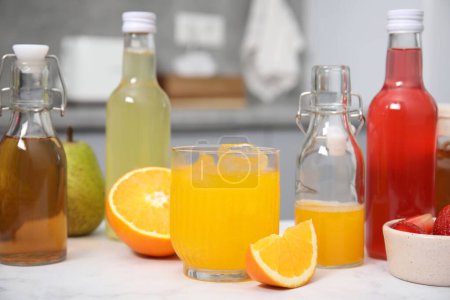 Leckere Kombucha in Glas, Flaschen und frischem Obst auf weißem Tisch
