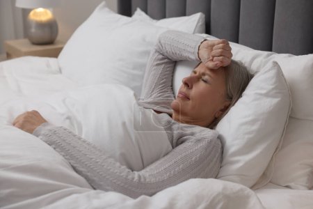 Wechseljahre. Frau leidet unter Kopfschmerzen im Bett