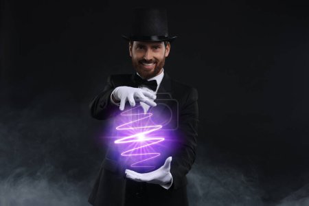 Magic and sorcery. Magician with fantastic light in smoke on dark background
