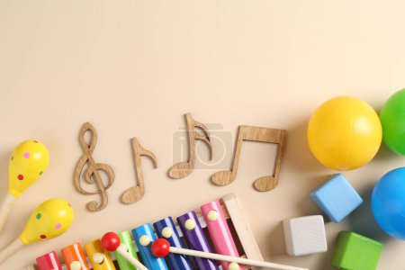 Téléchargez les photos : Concept de chanson de bébé. Notes en bois, xylophone pour enfants et jouets sur fond beige, pose à plat. Espace pour le texte - en image libre de droit