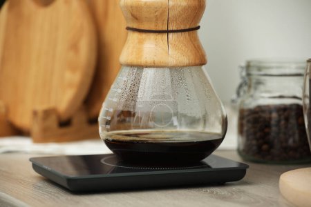 Photo for Glass chemex coffeemaker with coffee and scales on table, closeup - Royalty Free Image