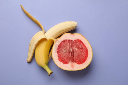 Banana and half of grapefruit on violet background, flat lay. Sex concept