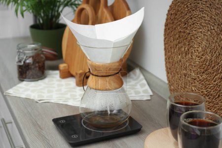 Téléchargez les photos : Cafetière chemex en verre avec filtre en papier, balances et verres de café sur comptoir en bois - en image libre de droit