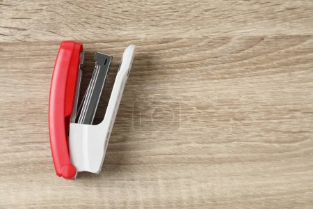Bright stapler on wooden table, top view. Space for text